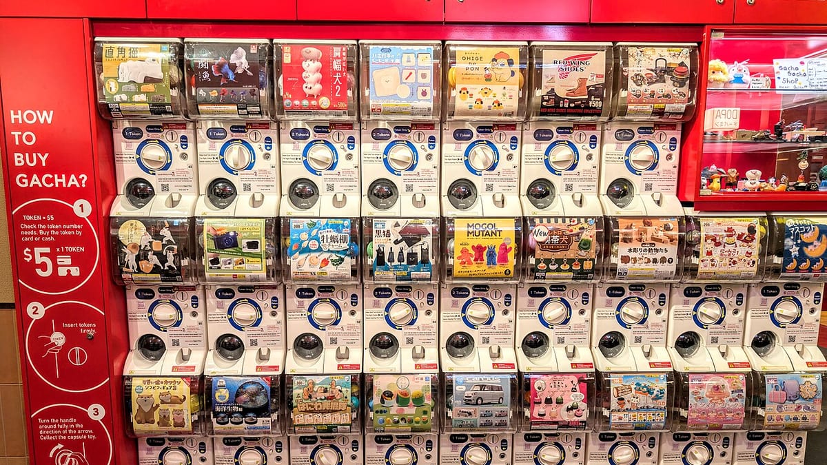 A wall of capsule-toy vending machines beside a red sign headed “How to buy gacha?”